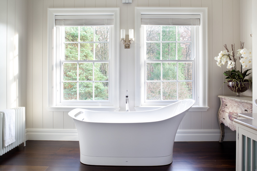 Inspiration for a transitional bathroom in London with dark hardwood floors and a freestanding tub.