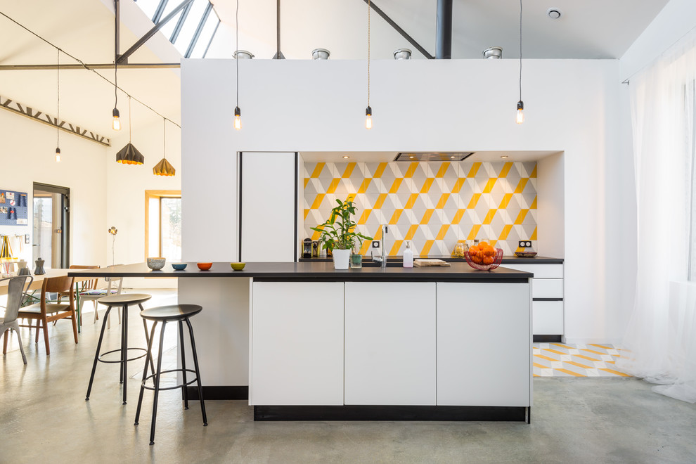 Inspiration for a mid-sized contemporary galley eat-in kitchen in Lyon with ceramic splashback, with island, flat-panel cabinets, white cabinets and multi-coloured splashback.