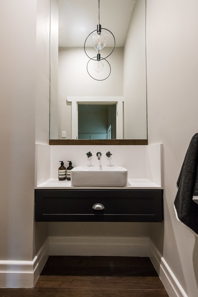 Small contemporary powder room in Melbourne with beaded inset cabinets, blue cabinets, a one-piece toilet, gray tile, porcelain tile, grey walls, medium hardwood floors, a vessel sink, engineered quartz benchtops and brown floor.