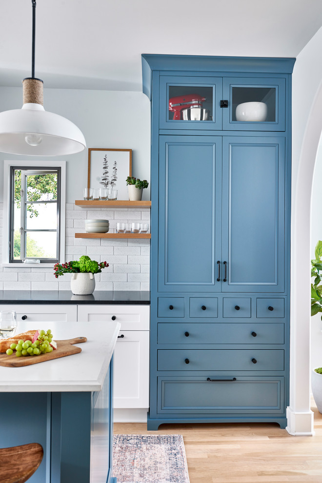 Ispirazione per un cucina con isola centrale chic con ante blu, paraspruzzi bianco e pavimento marrone