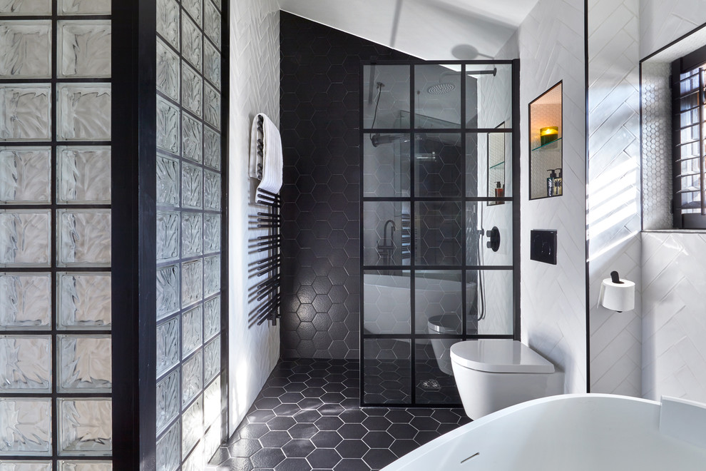Mid-sized contemporary master wet room bathroom in London with a wall-mount toilet, white walls, black floor, an open shower, black and white tile, medium wood cabinets, a freestanding tub, porcelain tile, porcelain floors, a vessel sink and wood benchtops.