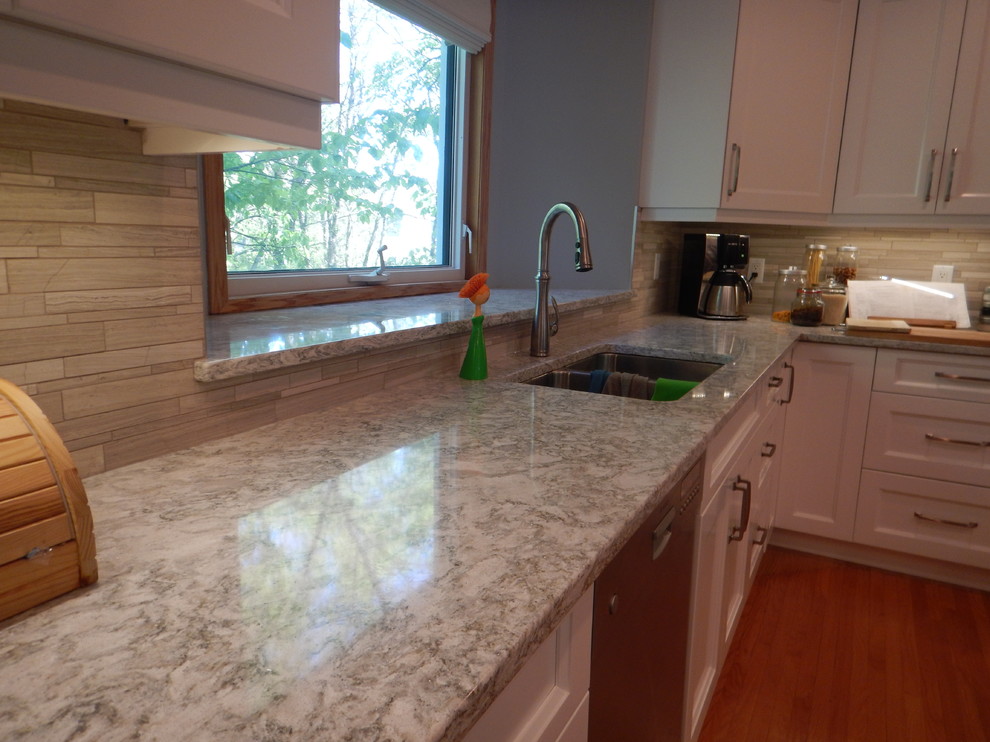 Large transitional l-shaped light wood floor eat-in kitchen photo with an undermount sink, recessed-panel cabinets, white cabinets, quartz countertops, gray backsplash, stone tile backsplash, stainless steel appliances and an island
