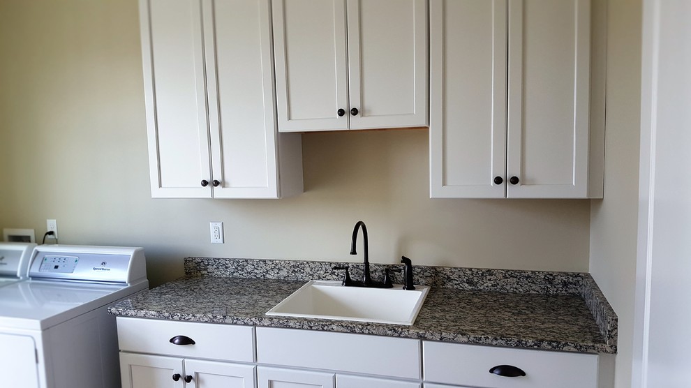 Large single-wall utility room in Richmond with an utility sink, shaker cabinets, white cabinets, granite benchtops, beige walls, light hardwood floors and a side-by-side washer and dryer.