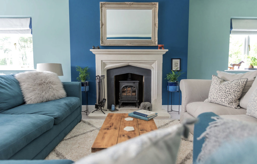 На фото: изолированная гостиная комната среднего размера в стиле рустика с синими стенами, ковровым покрытием, стандартным камином, фасадом камина из камня, телевизором на стене, бежевым полом, балками на потолке и кирпичными стенами