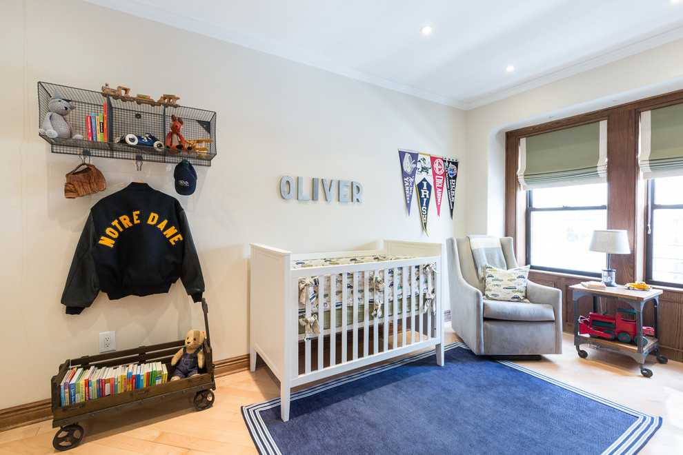 Design ideas for a mid-sized traditional nursery for boys in New York with beige walls and light hardwood floors.