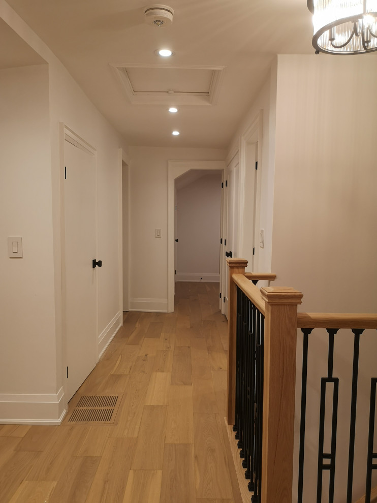 This is an example of a large classic home studio in Toronto with beige walls, medium hardwood flooring, a corner fireplace, a stone fireplace surround, a built-in desk and beige floors.