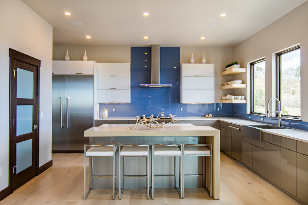 Photo of an expansive contemporary u-shaped open plan kitchen in Other with a farmhouse sink, flat-panel cabinets, grey cabinets, quartz benchtops, blue splashback, glass sheet splashback, stainless steel appliances, light hardwood floors, with island and beige floor.