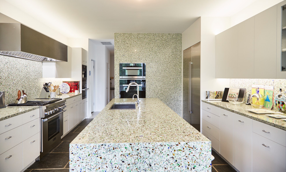 Mid-sized contemporary galley separate kitchen in New York with an undermount sink, flat-panel cabinets, white cabinets, recycled glass benchtops, green splashback, glass sheet splashback, stainless steel appliances, slate floors, with island and blue floor.