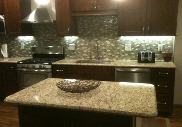 Large transitional l-shaped dark wood floor and brown floor eat-in kitchen photo with an undermount sink, shaker cabinets, dark wood cabinets, multicolored backsplash, stainless steel appliances and an island
