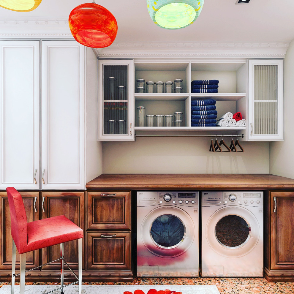 Photo of a traditional laundry room with glass-front cabinets, a side-by-side washer and dryer and brown benchtop.