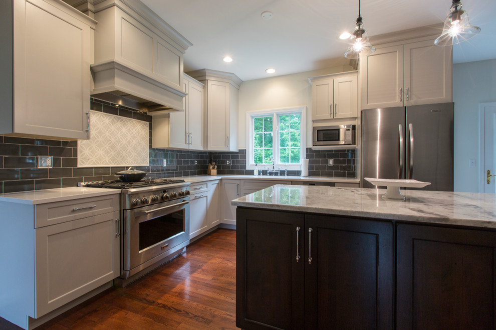 Mid-sized transitional l-shaped eat-in kitchen in Bridgeport with an undermount sink, recessed-panel cabinets, grey cabinets, granite benchtops, black splashback, ceramic splashback, stainless steel appliances, medium hardwood floors and with island.