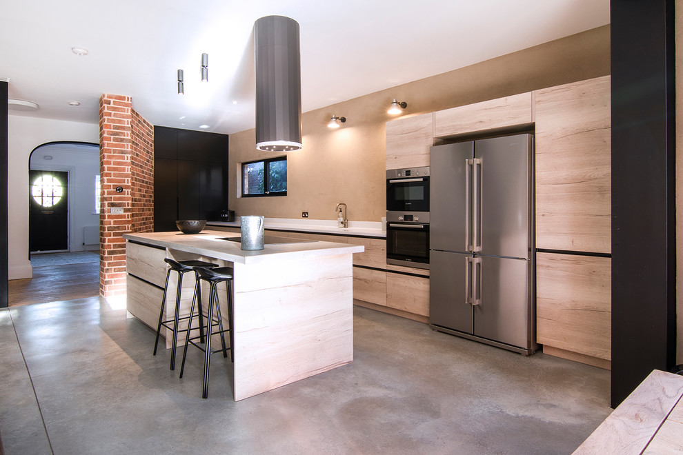 Mid-sized industrial single-wall eat-in kitchen in London with an undermount sink, light wood cabinets, concrete benchtops, black appliances, concrete floors, with island and grey benchtop.