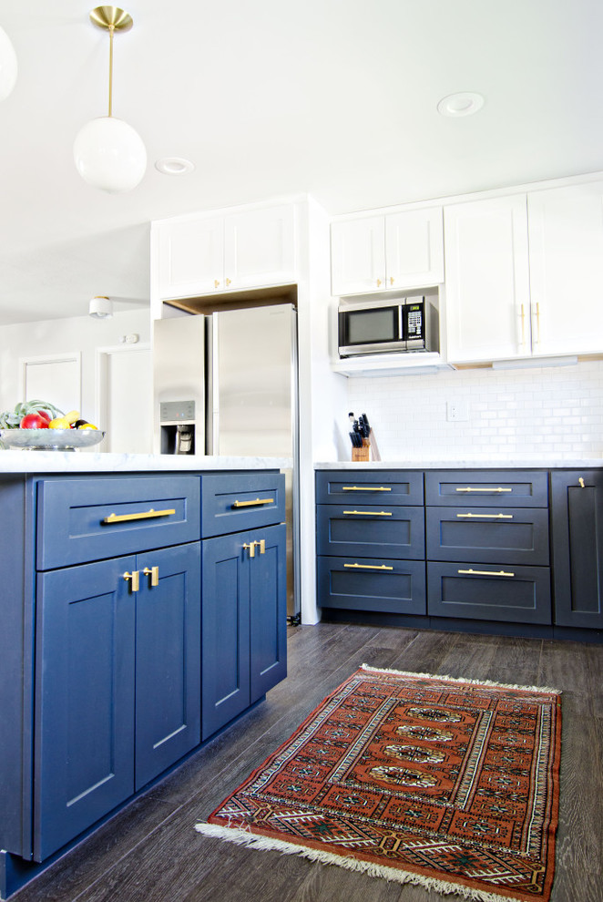 This is an example of a mid-sized midcentury l-shaped eat-in kitchen in San Francisco with a farmhouse sink, shaker cabinets, blue cabinets, marble benchtops, white splashback, ceramic splashback, stainless steel appliances, dark hardwood floors and with island.