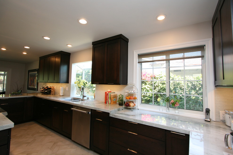 Example of a mid-sized transitional l-shaped porcelain tile kitchen design in Orange County with a double-bowl sink, recessed-panel cabinets, dark wood cabinets, quartzite countertops, white backsplash, glass tile backsplash, stainless steel appliances and no island