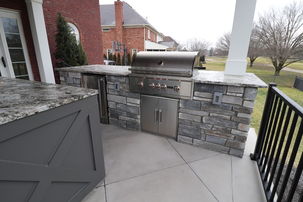 Photo of a large traditional backyard patio in Louisville with an outdoor kitchen, concrete pavers and a roof extension.