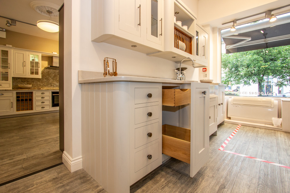 Photo of a small traditional single-wall separate kitchen in Cheshire with a farmhouse sink, shaker cabinets, grey cabinets, solid surface benchtops, grey splashback, white appliances, no island and white benchtop.
