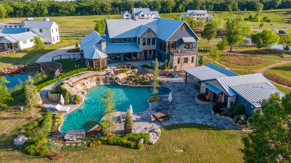 Photo of an expansive country backyard custom-shaped natural pool in Oklahoma City with with a pool and natural stone pavers.