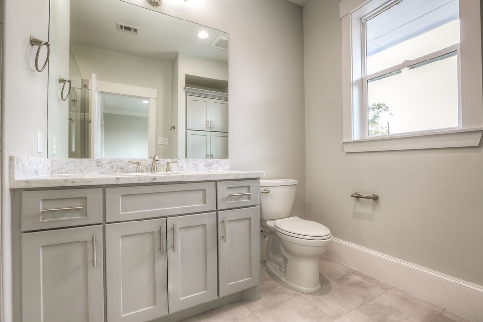 Example of a mid-sized transitional white tile and ceramic tile ceramic tile and gray floor alcove shower design in Houston with shaker cabinets, white cabinets, a two-piece toilet, white walls, an undermount sink, granite countertops and a hinged shower door