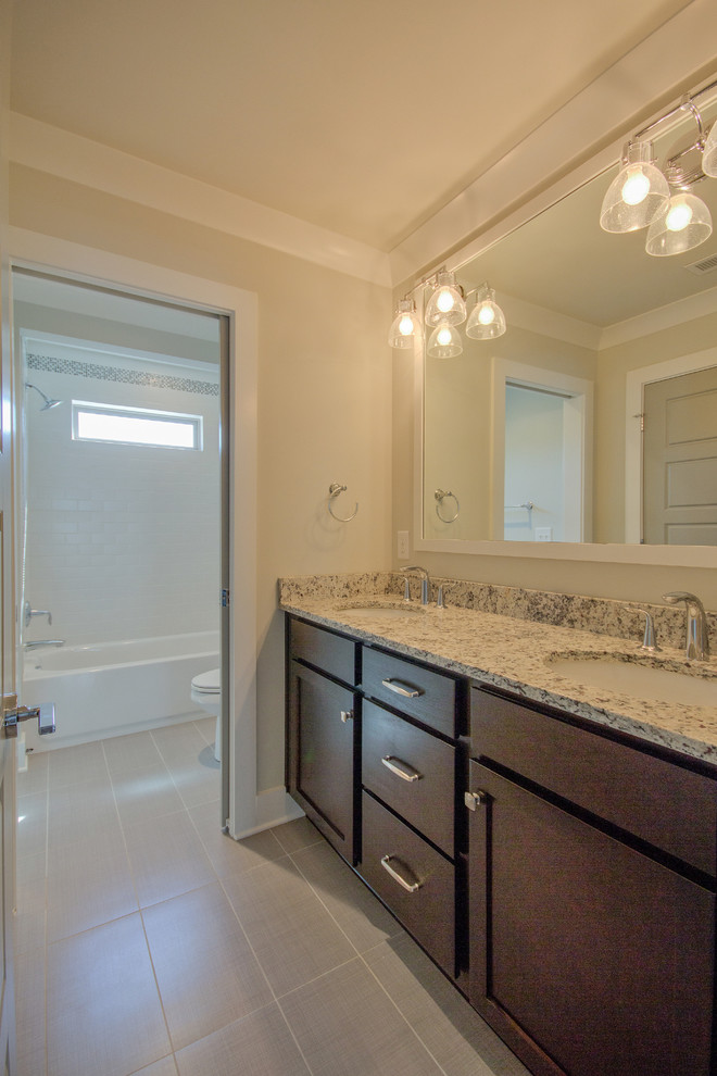 Mid-sized arts and crafts bathroom in Nashville with an undermount sink, shaker cabinets, dark wood cabinets, granite benchtops, an alcove tub, a shower/bathtub combo, a two-piece toilet, gray tile, ceramic tile, grey walls and porcelain floors.