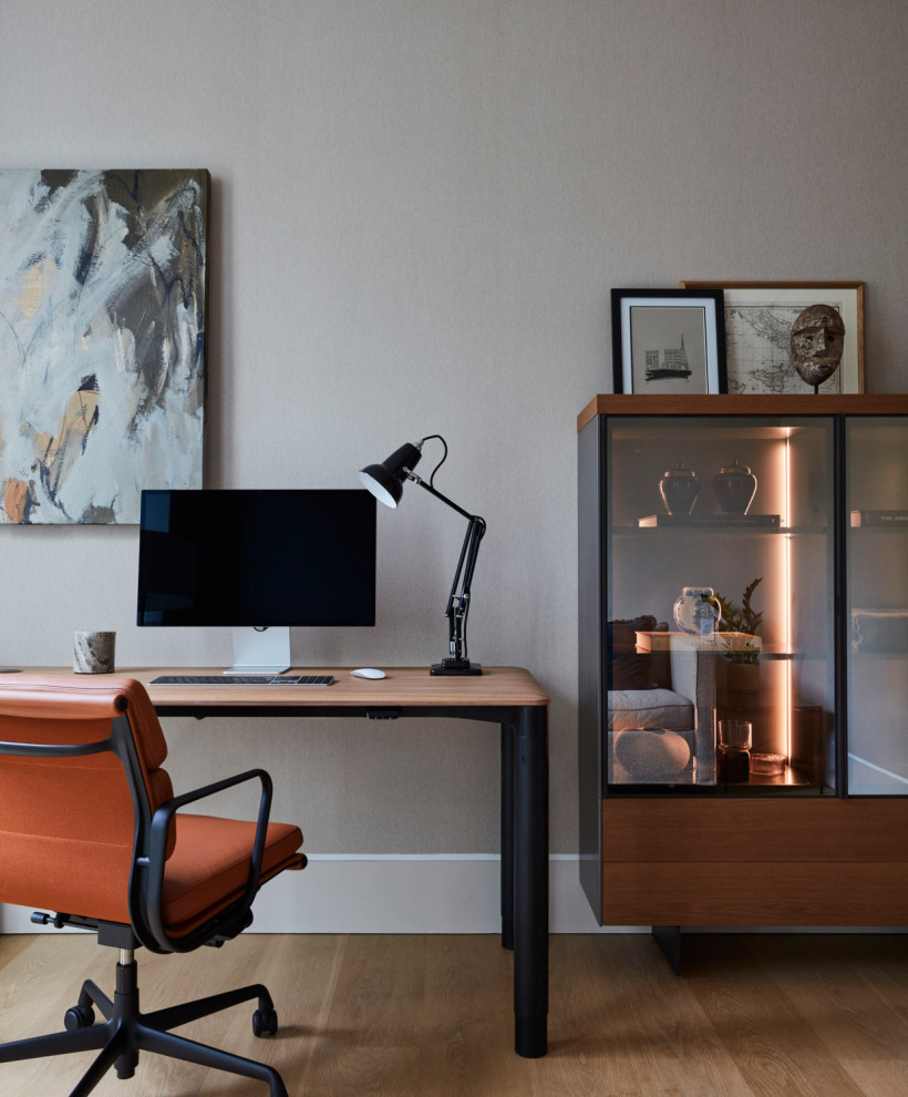 This is an example of a medium sized contemporary study in London with beige walls, light hardwood flooring, a freestanding desk and wallpapered walls.