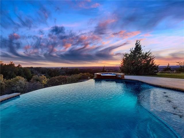 Design ideas for an expansive eclectic backyard custom-shaped infinity pool in Dallas with a hot tub and concrete slab.
