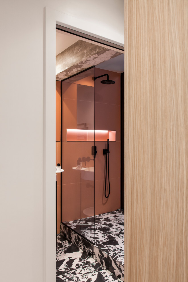 Example of a mid-sized trendy master orange tile and ceramic tile marble floor, black floor and single-sink doorless shower design in Paris with open cabinets, white cabinets, a wall-mount toilet, orange walls, a pedestal sink, solid surface countertops, a hinged shower door, white countertops, a niche and a freestanding vanity