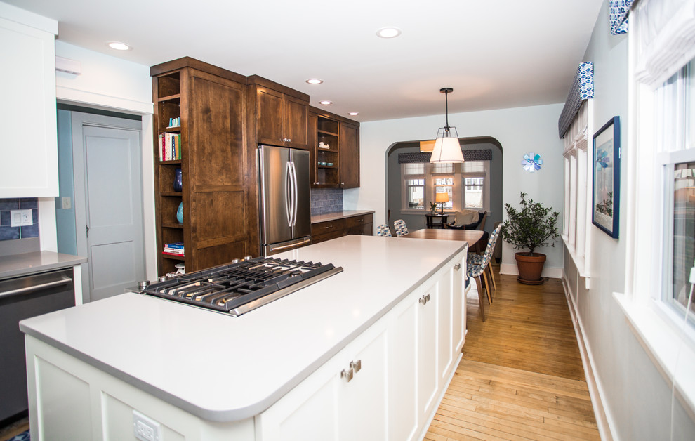 Inspiration for a mid-sized transitional galley light wood floor enclosed kitchen remodel in Milwaukee with an undermount sink, shaker cabinets, medium tone wood cabinets, quartz countertops, blue backsplash, ceramic backsplash, stainless steel appliances and an island