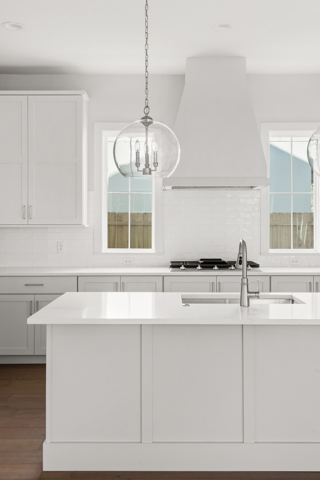 Large transitional u-shaped medium tone wood floor and brown floor kitchen pantry photo in Orlando with an undermount sink, shaker cabinets, white cabinets, marble countertops, white backsplash, porcelain backsplash, stainless steel appliances, an island and white countertops