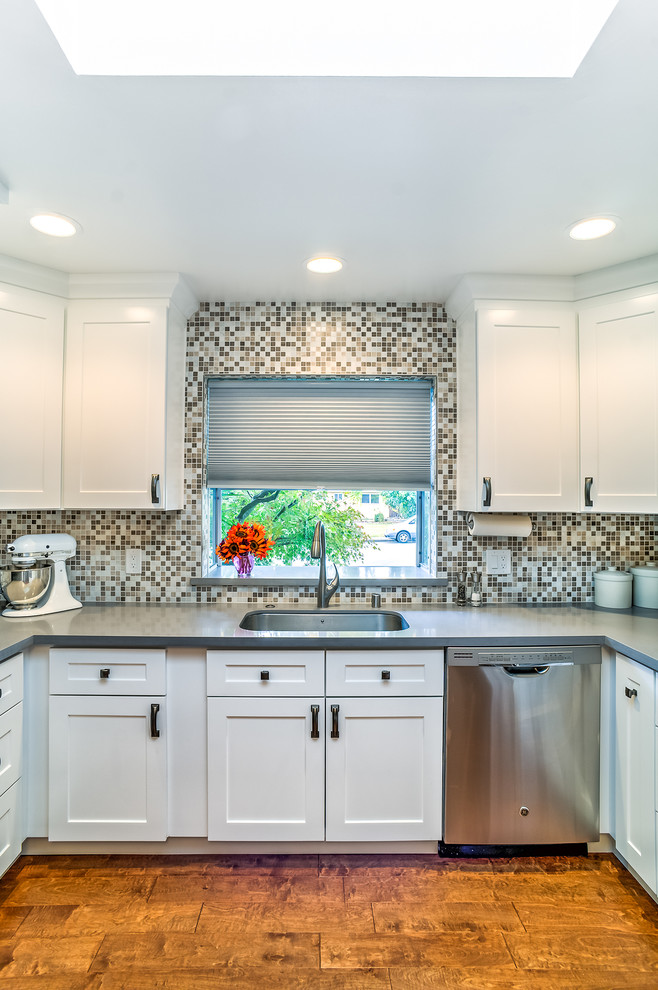 Inspiration for a small transitional u-shaped medium tone wood floor enclosed kitchen remodel in San Francisco with a single-bowl sink, shaker cabinets, white cabinets, quartz countertops, multicolored backsplash, stone tile backsplash, stainless steel appliances and no island