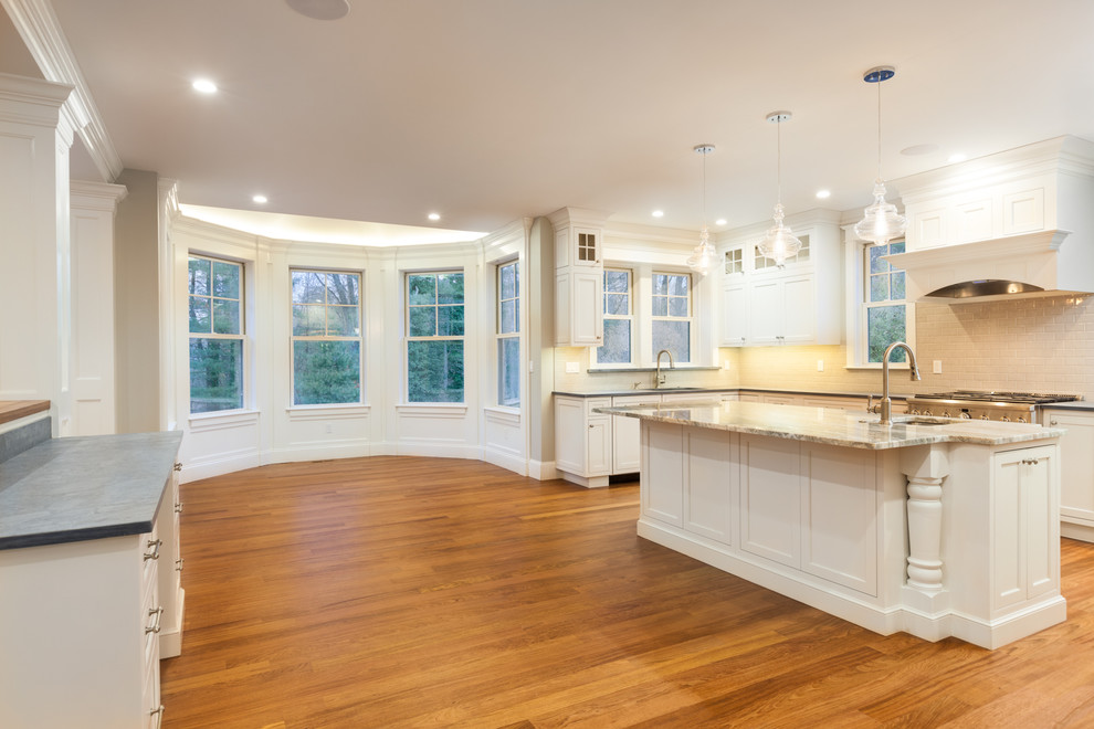 This is an example of a large traditional l-shaped kitchen in Boston with an undermount sink, beaded inset cabinets, white cabinets, soapstone benchtops, grey splashback, ceramic splashback, stainless steel appliances, medium hardwood floors, with island, brown floor and grey benchtop.