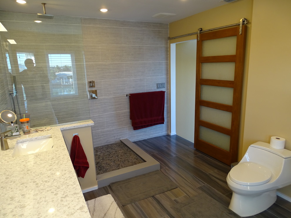 Design ideas for a mid-sized contemporary master bathroom in Tampa with flat-panel cabinets, medium wood cabinets, an open shower, porcelain tile, porcelain floors, an undermount sink, engineered quartz benchtops, a one-piece toilet, gray tile, white tile and yellow walls.