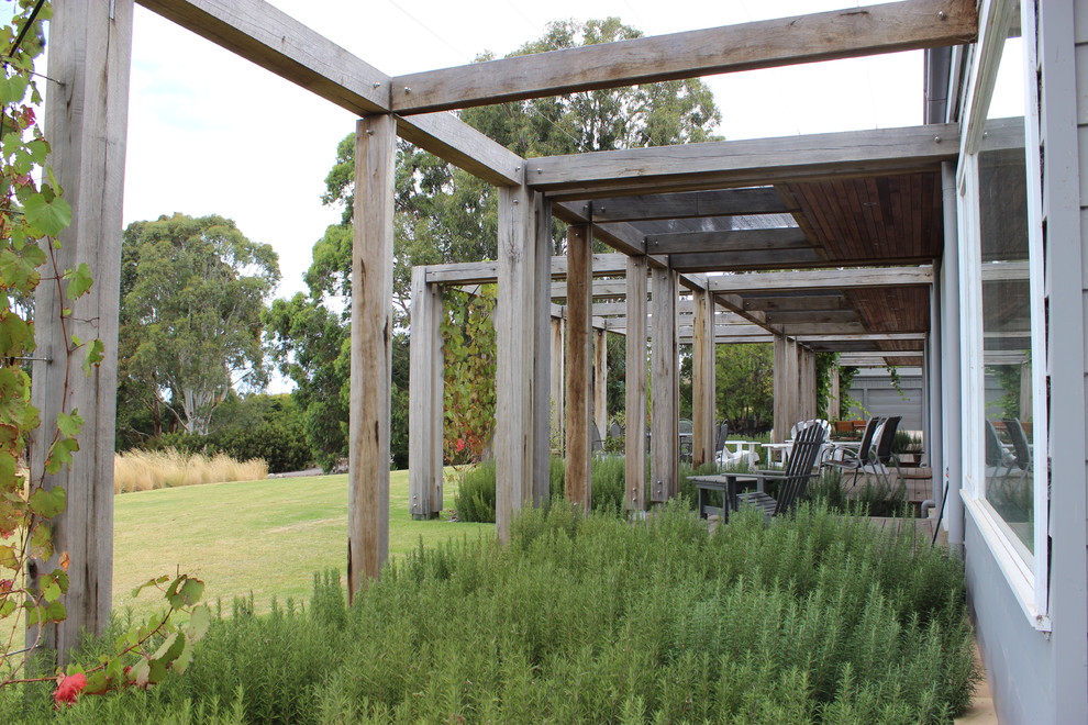 Photo of a large eclectic front yard patio in Melbourne with decking and a pergola.