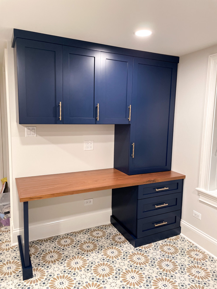 This is an example of a large country utility room in Chicago with shaker cabinets, blue cabinets, wood benchtops, white walls, a side-by-side washer and dryer, multi-coloured floor and an integrated sink.