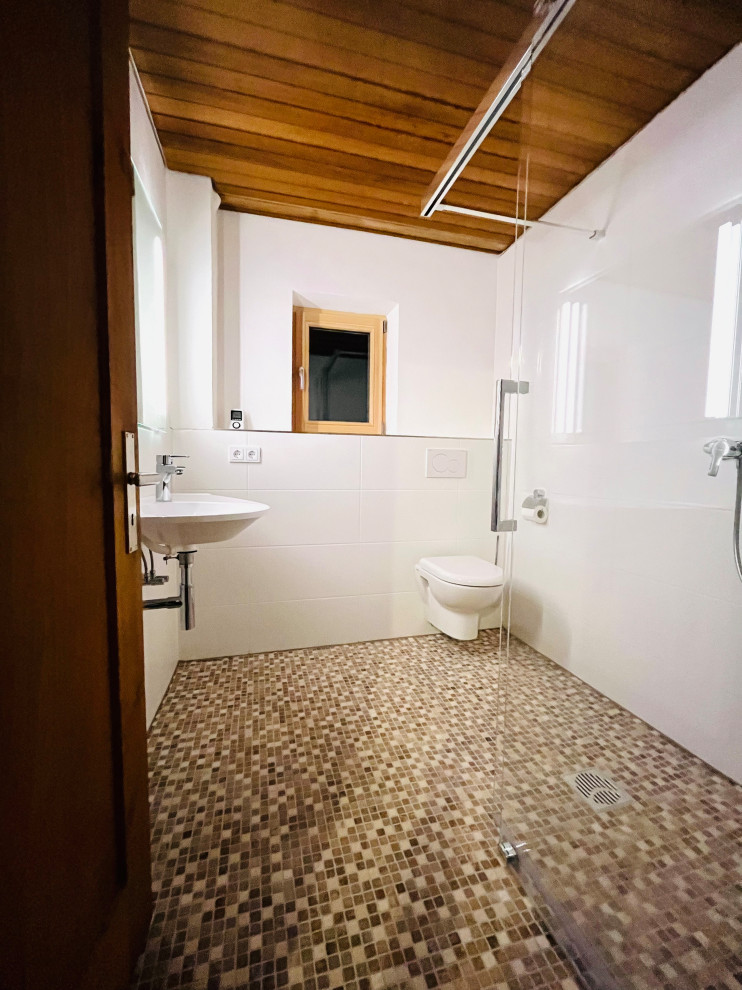 Cette image montre une petite salle de bain design avec une douche à l'italienne, WC suspendus, un carrelage blanc, des carreaux de céramique, un mur blanc, un sol en carrelage de terre cuite, un lavabo suspendu, un plan de toilette en surface solide, un sol beige, une cabine de douche à porte coulissante, un plan de toilette blanc, meuble simple vasque, meuble-lavabo suspendu et un plafond en lambris de bois.