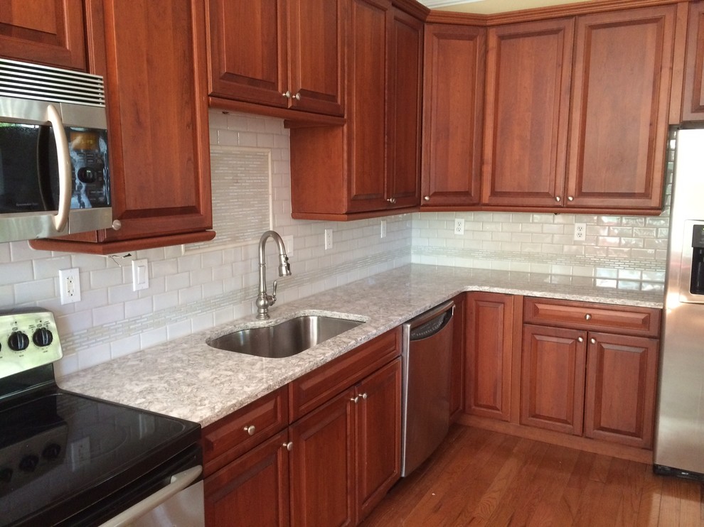 Transitional l-shaped dark wood floor kitchen photo in Bridgeport with an undermount sink, raised-panel cabinets, granite countertops, gray backsplash and ceramic backsplash