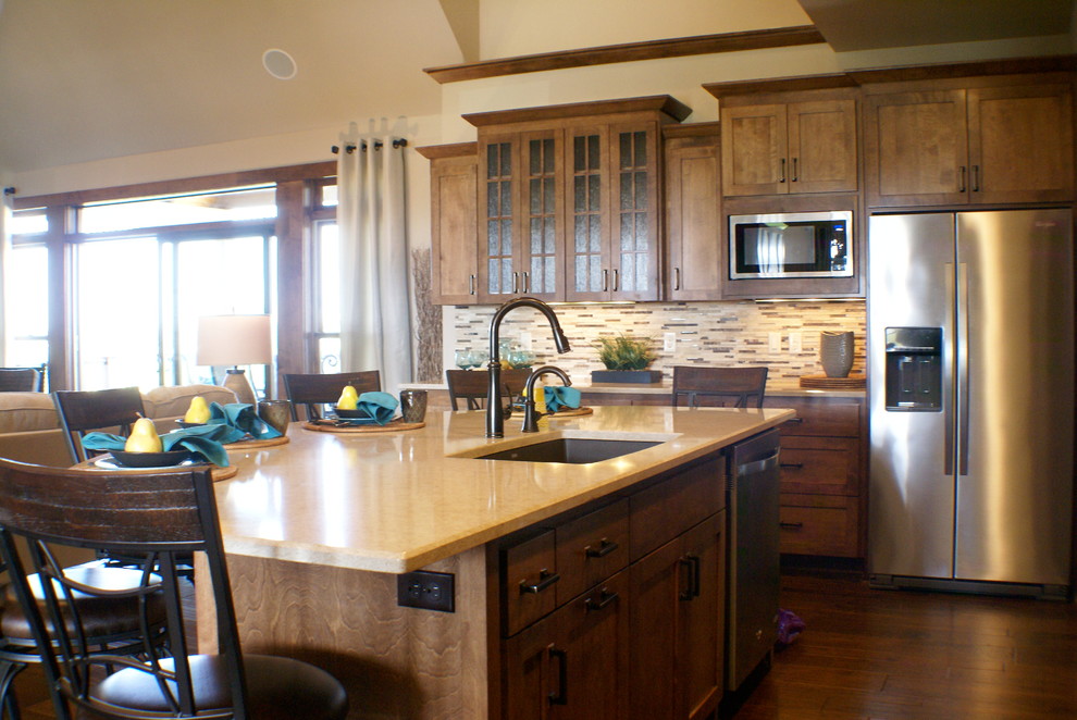 This is an example of a mid-sized arts and crafts u-shaped open plan kitchen in Milwaukee with an undermount sink, shaker cabinets, medium wood cabinets, limestone benchtops, beige splashback, matchstick tile splashback, stainless steel appliances, medium hardwood floors and with island.