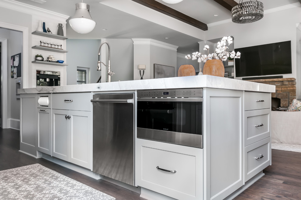 This is an example of a traditional galley eat-in kitchen in Atlanta with a single-bowl sink, shaker cabinets, grey cabinets, quartz benchtops, white splashback, marble splashback, stainless steel appliances, dark hardwood floors, with island, brown floor and white benchtop.