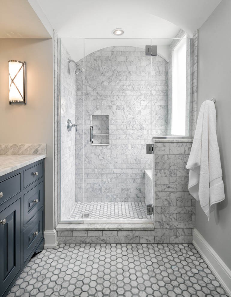 This is an example of a mid-sized traditional master bathroom in Cincinnati with blue cabinets, an open shower, a two-piece toilet, white tile, marble, white walls, marble floors, marble benchtops and a hinged shower door.