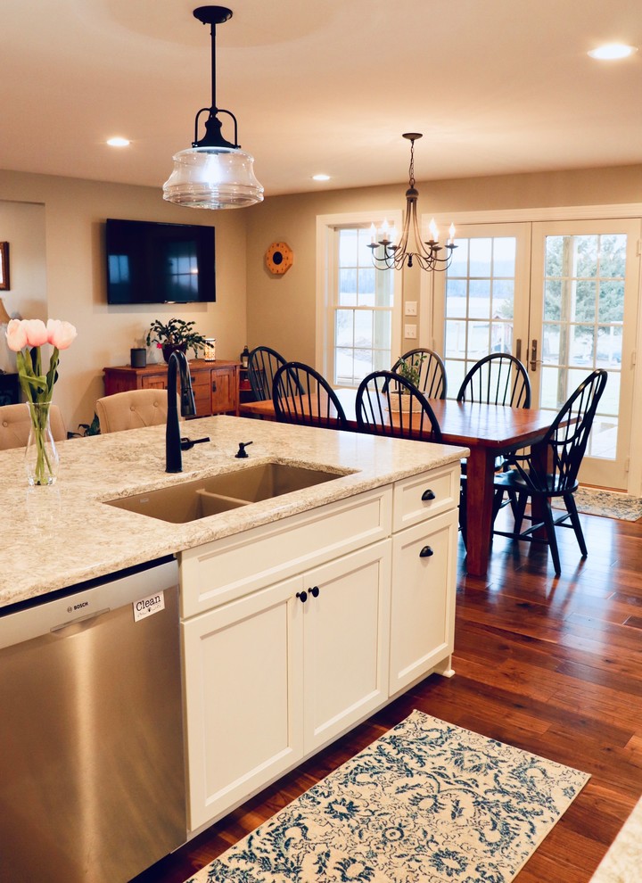 Photo of an expansive country eat-in kitchen in New York with an undermount sink, shaker cabinets, white cabinets, quartz benchtops, white splashback, ceramic splashback, stainless steel appliances, medium hardwood floors, with island, multi-coloured floor and white benchtop.