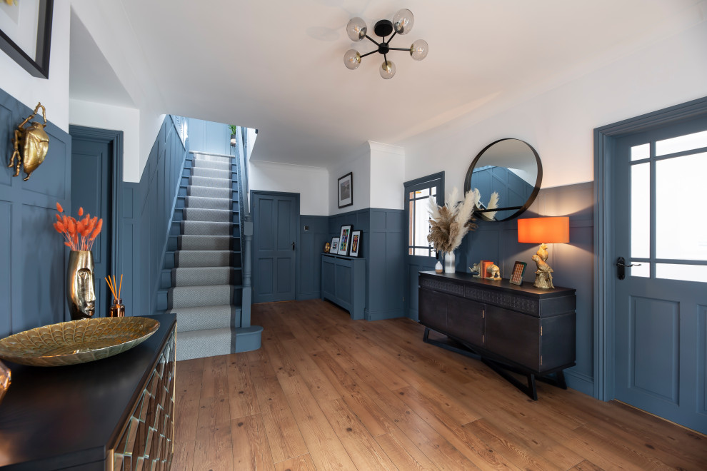 エセックスにあるお手頃価格の広いコンテンポラリースタイルのおしゃれな廊下 (青い壁、ラミネートの床、茶色い床) の写真