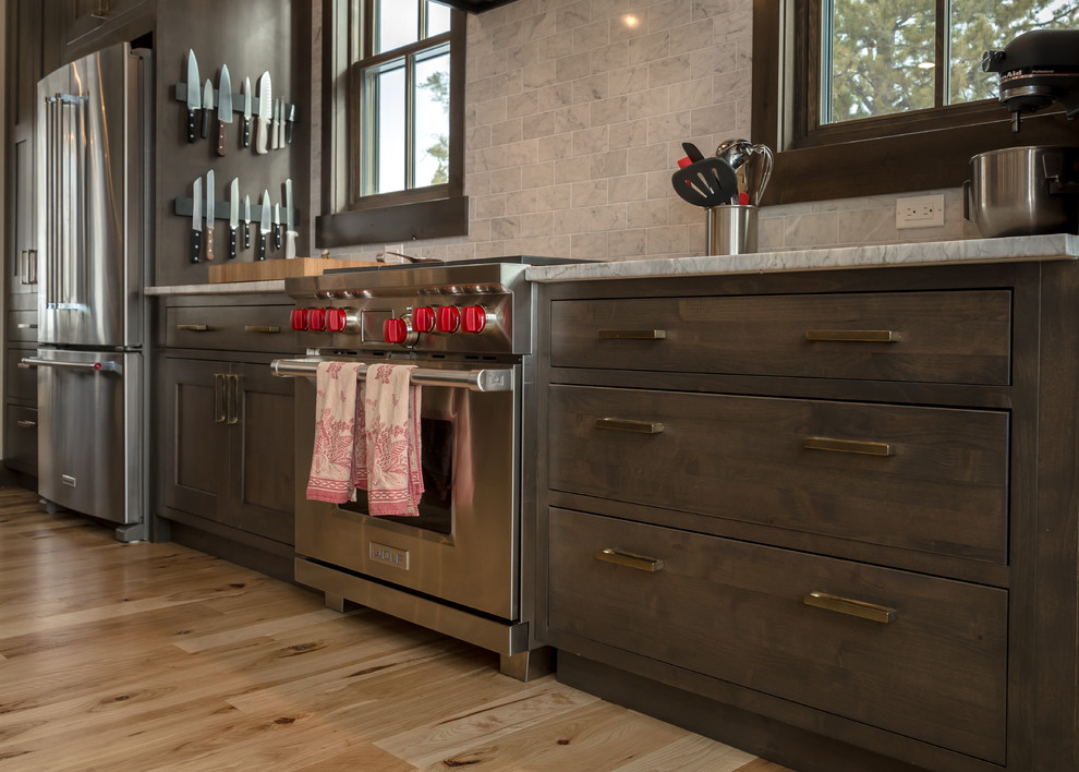 Open concept kitchen - large rustic l-shaped light wood floor and beige floor open concept kitchen idea in Denver with an undermount sink, shaker cabinets, dark wood cabinets, quartz countertops, beige backsplash, subway tile backsplash, stainless steel appliances, an island and white countertops