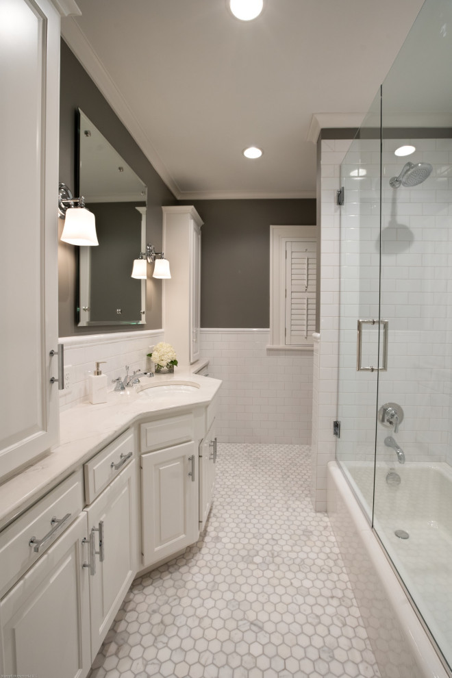 Inspiration for a mid-sized traditional bathroom in Kansas City with raised-panel cabinets, white cabinets, an alcove tub, a shower/bathtub combo, a two-piece toilet, white tile, ceramic tile, grey walls, marble floors, an undermount sink, engineered quartz benchtops, grey floor and grey benchtops.