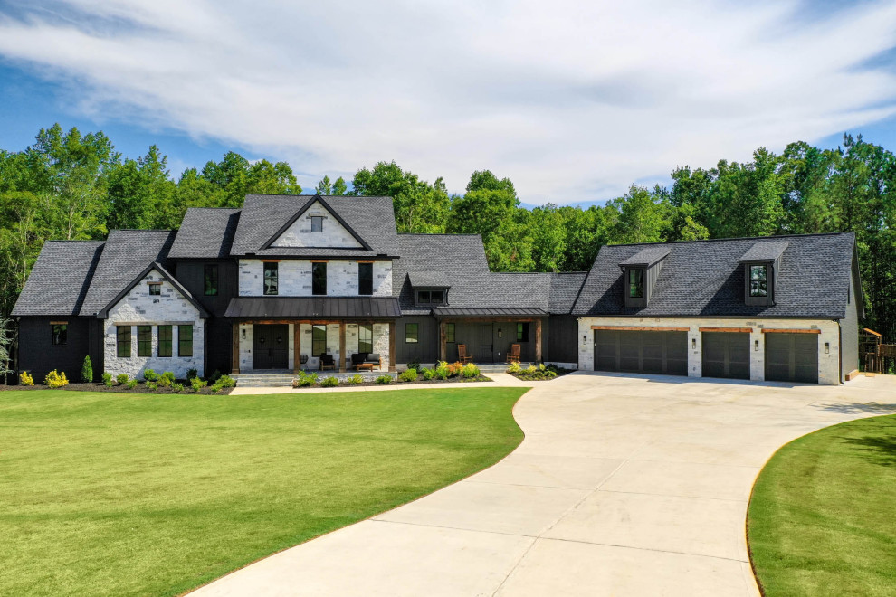 This is an example of an expansive modern three-storey brick black house exterior in Atlanta with a mixed roof, a black roof and board and batten siding.