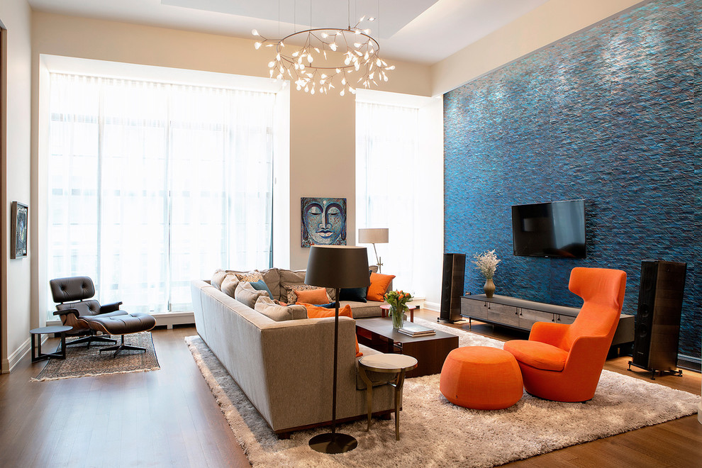 Trendy open concept medium tone wood floor living room photo in New York with blue walls and a wall-mounted tv