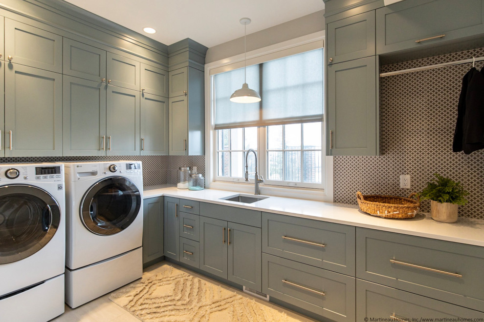 Inspiration for a large transitional l-shaped utility room in Salt Lake City with a drop-in sink, recessed-panel cabinets, blue cabinets, quartzite benchtops, beige splashback, porcelain splashback, grey walls, porcelain floors, a side-by-side washer and dryer, beige floor and white benchtop.