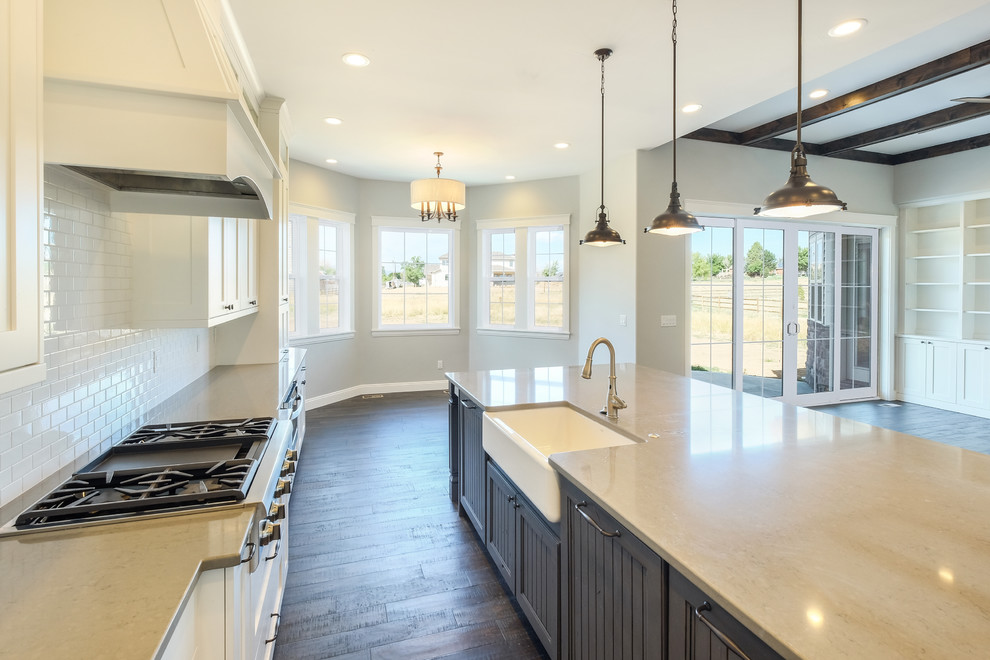 Inspiration for a large country single-wall open plan kitchen in Denver with a farmhouse sink, shaker cabinets, white cabinets, quartzite benchtops, white splashback, subway tile splashback, stainless steel appliances, dark hardwood floors and with island.