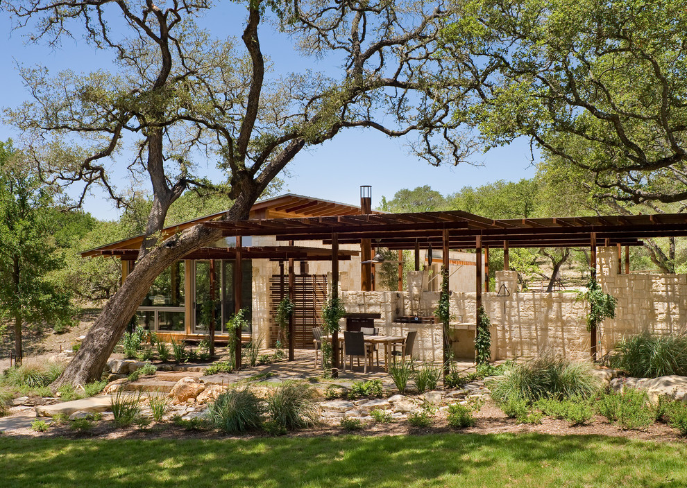 This is an example of a country patio in Austin with a pergola.