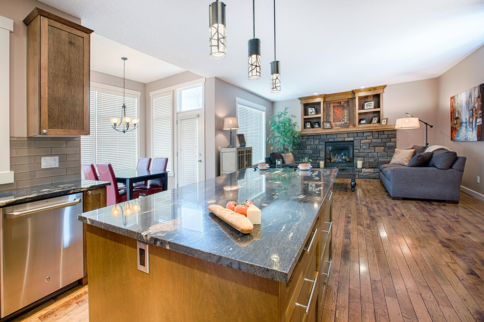 Mid-sized mountain style u-shaped medium tone wood floor and brown floor eat-in kitchen photo in Calgary with an undermount sink, shaker cabinets, medium tone wood cabinets, granite countertops, gray backsplash, glass tile backsplash, stainless steel appliances and an island