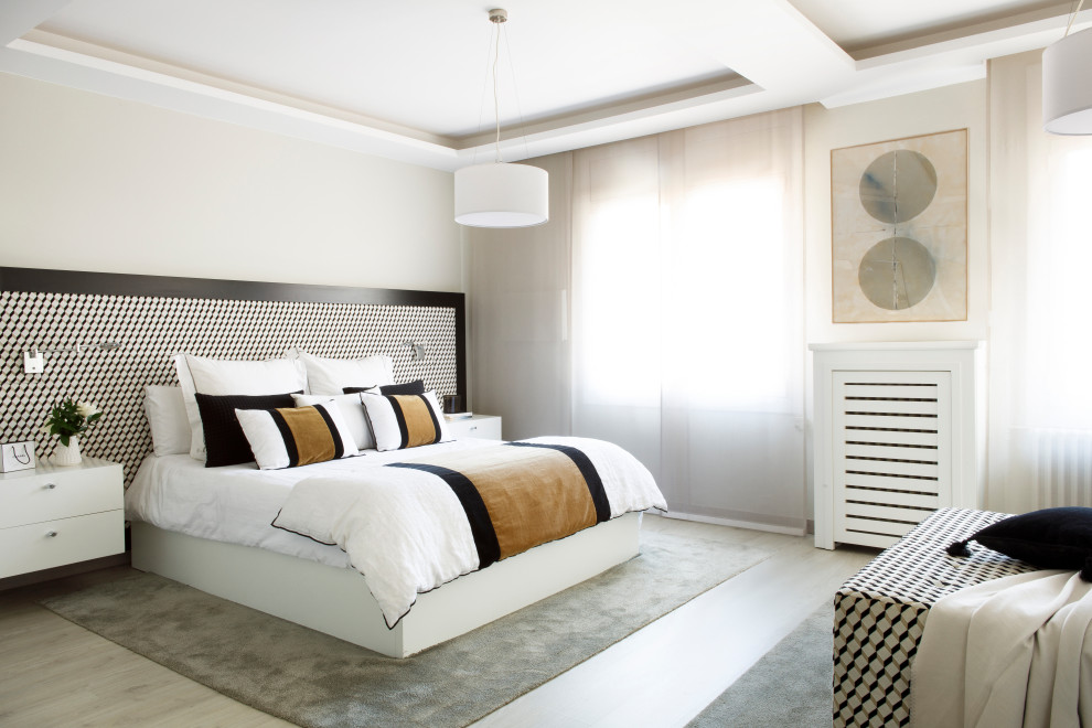 This is an example of a contemporary master bedroom in Barcelona with beige walls and light hardwood floors.