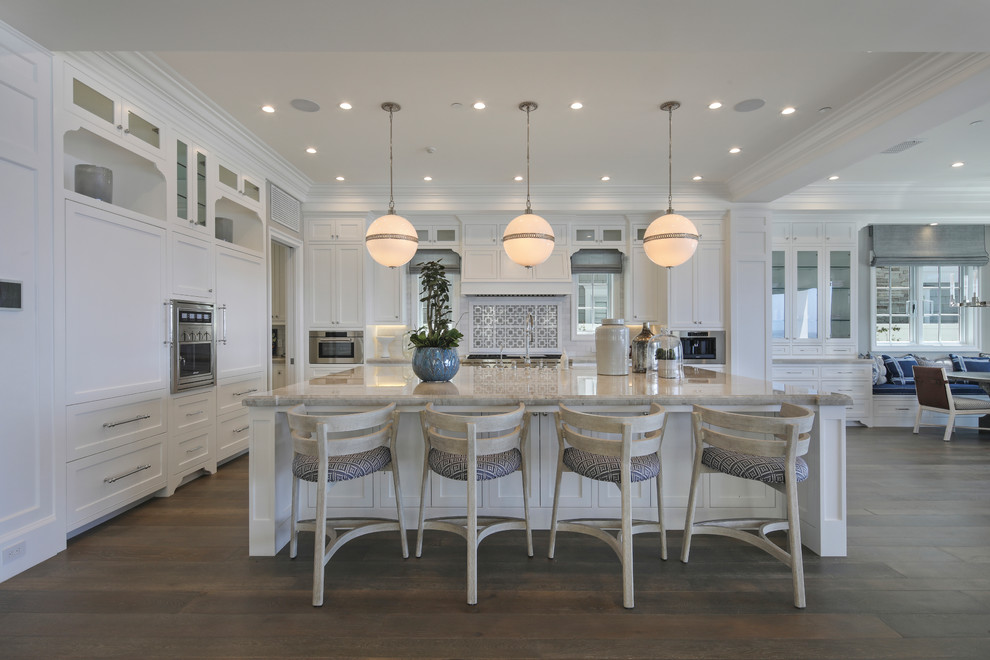 Beach style l-shaped open plan kitchen in Orange County with recessed-panel cabinets, white cabinets, dark hardwood floors, with island, brown floor and beige benchtop.
